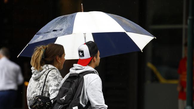 Members of the public shelter in the Brisbane CBD from rain on Monday. Sky News Weather has forecast widespread falls between 60-100mm, which could go as high as 200mm in parts of the state. Picture: NCA NewsWire/Tertius Pickard