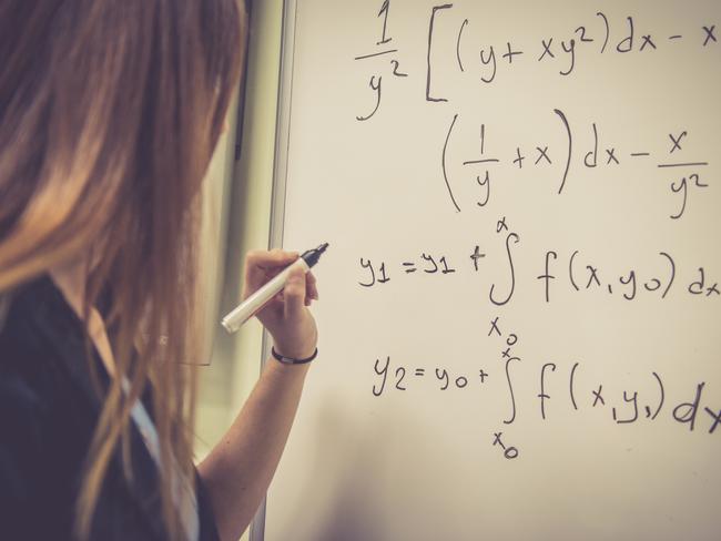 CAREERS: Young female student, teacher, with long hair doing math at the whiteboard, Istanbul, Turkey. Rear view, copy space. Nikon D800, full frame, XXXL.