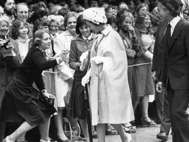 Royal visit and Silver Jubilee tour of South Australia by Queen Elizabeth II and the Duke of Edinburgh, Mar 1977. The Queen walks down a line of well-wishers in Rundle Mall with SA Premier Don Dunstan on her final day in Adelaide, 23 Mar 1977. Here a woman steps out of the barricade to give a gift to the Queen whilst curtseying. (Pic by unidentified staff photographer)