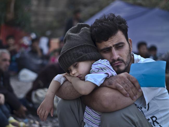 A Syrian refugee child sleeps on his father's arms while waiting at a resting point to board a bus in Greece. One of the lucky children who escaped Syria. Picture: AP/Muhammed Muheisen