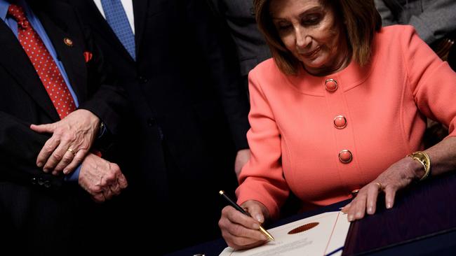 Sign of the times … speaker of the House Nancy Pelosi signs articles of impeachment of US President Donald Trump using custom gold pens. Picture: Brendan Smialowski/AFP