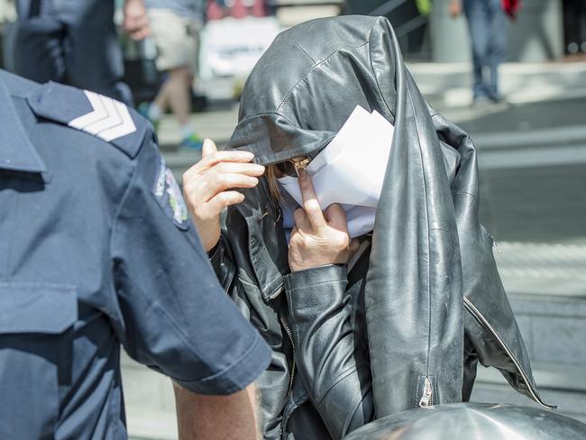 A woman leaves West Melbourne police station with a leather jacket over her head. Picture: Jason Edwards.