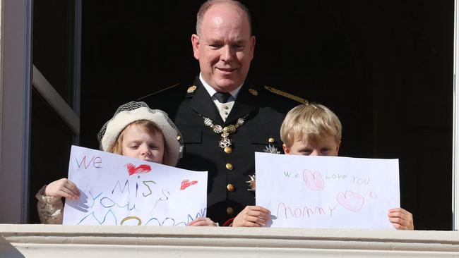 Prince Albert II of Monaco, Princess Gabriella and Prince Jacques stand with a message for Princess Charlene at the balcony of Monaco Palace.