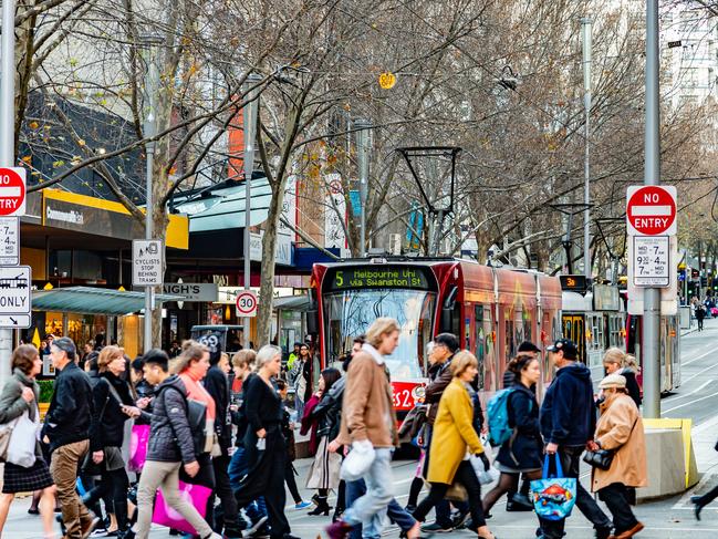 Melbourne, Victoria, Australia, July 14 2018: Five Public Transport Victoria trams are on Swanston Street while pedestrians cross the road at the intersection of Bourke Street.