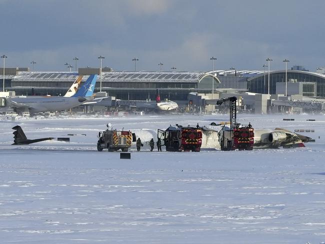 Pearson International Airport firefighters work on the upside down Delta Air Lines plane. Picture: The Canadian Press via AP