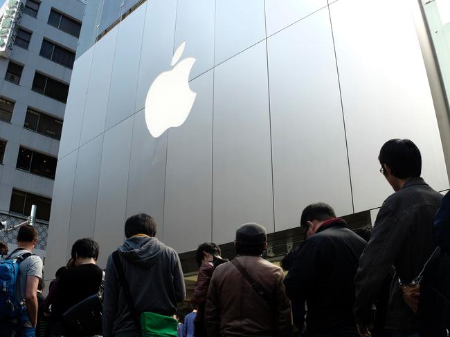 Customers queue up for Apple's new iPhone SE in front of an Apple store in the Ginza shopping district in Tokyo on March 31, 2016.   The iPhone SE goes on sale in Japan. / AFP PHOTO / KAZUHIRO NOGI