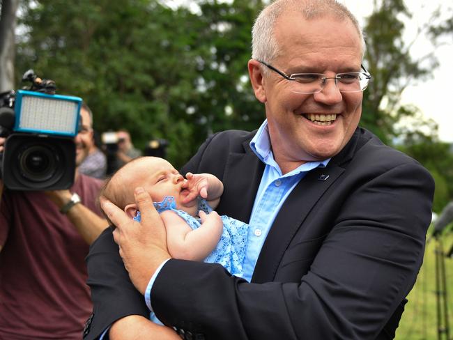 Mr Morrison holds baby Georgie after a press conference in Windaroo, 40km south of Brisbane on Saturday. Picture: Mick Tsikas