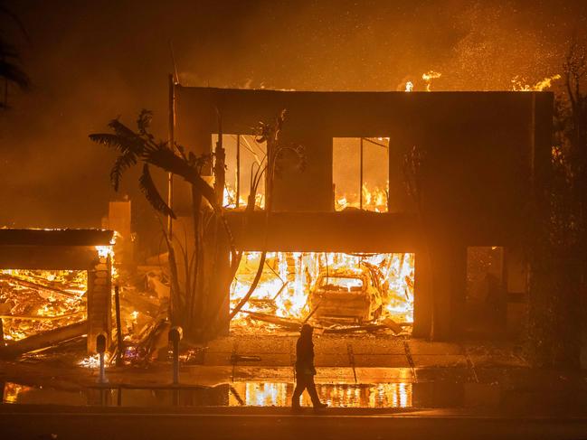 A firefighter watches the flames from the Palisades fire burning homes on the Pacific Coast Highway. Picture: Apu Gomes/Getty Images/AFP