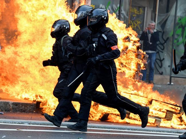 French riot police run past a fire during a demonstration in Paris. Picture: AFP