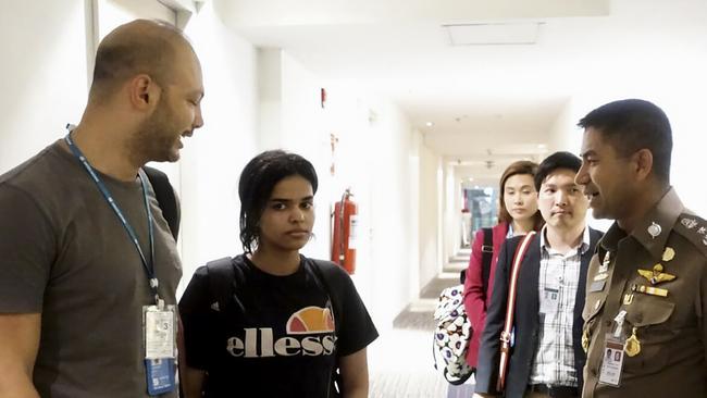 Saudi woman Rahaf Mohammed Alqunun, second from left, being escorted by a Thai immigration officer, right, and United Nations High Commissioner for Refugees at Bangkok international airport. This photo was released by the Thai Immigration Bureau. Via AFP  