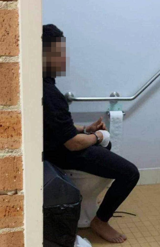 The accused teen sitting on a toilet with a bandaged hand.