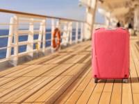 Pink passenger suitcase standing on the wooden deck of an cruise ship at holidays