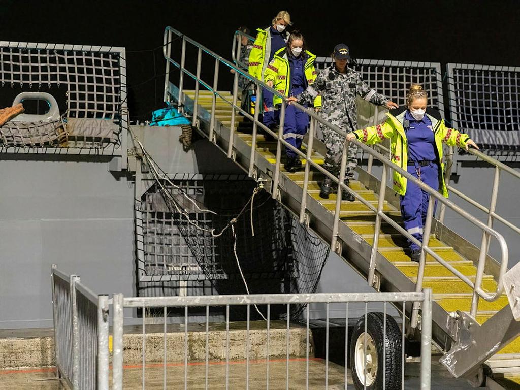 One of two sailors found clinging to their upturned yacht is escorted off destroyer HMAS Brisbane by NSW Ambulance Service paramedics. Source: Defence Department