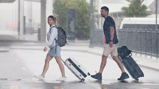 Kate Davey and Chris Davey from Melbourne arrive at a very wet Cairns Airport for their flight on Tuesday afternoon. Picture: Brendan Radke