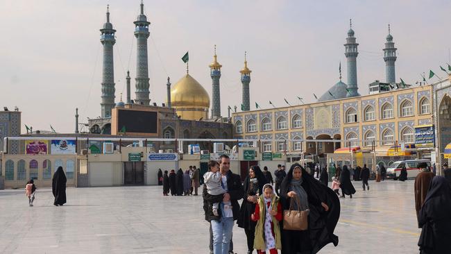 People walk in front of the Fatima Masumeh Shrine in the holy Iranian city of Qom, south of Tehran. Picture: AFP.