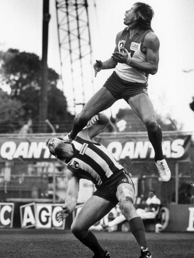 Warwick Capper, aka ‘The Wiz’, flies over Mick Martyn. Picture: BRUCE HOWARD