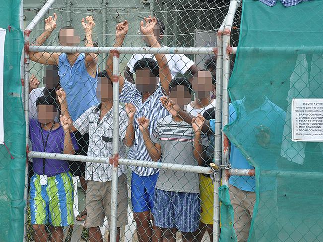 Asylum seekers stare at media from behind a fence on Manus Island. Picture: AAP Image/Eoin Blackwell