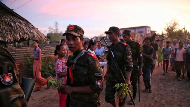 Thankful residents of a village in Myanmar’s Sagaing region give flowers to anti-coup fighters. Picture: AFP