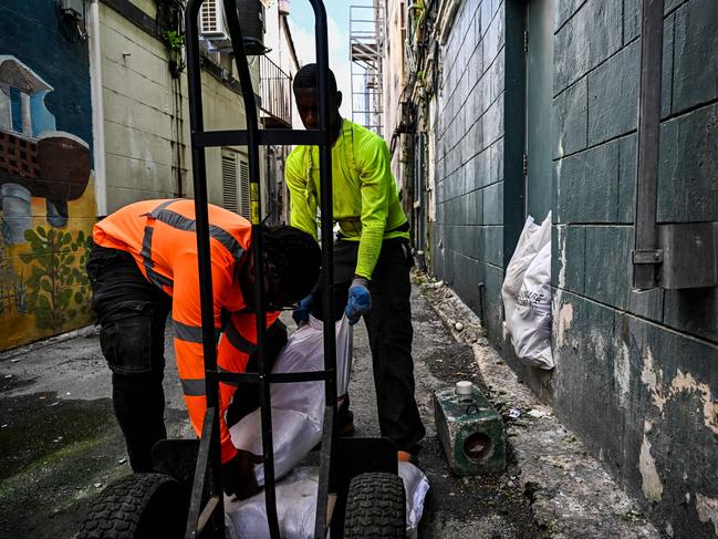 Workers put bags of sand at the back door of a shop in Bridgetown, Barbados. (Photo by CHANDAN KHANNA / AFP)