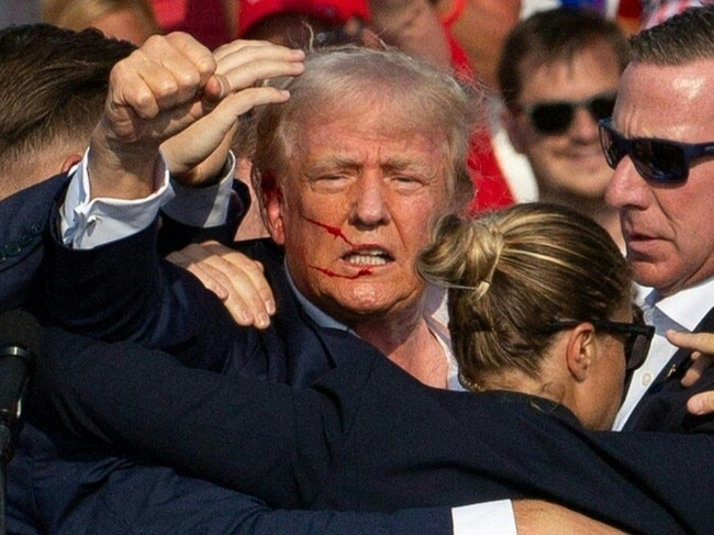 Republican candidate Donald Trump is seen with blood on his face surrounded by secret service agents as he is taken off the stage at a campaign event at Butler Farm Show Inc. in Butler, Pennsylvania, July 13, 2024. The suspected shooter who wounded Republican presidential candidate Donald Trump at a rally is dead, US media reported Saturday, along with one bystander. (Photo by Rebecca DROKE / AFP)