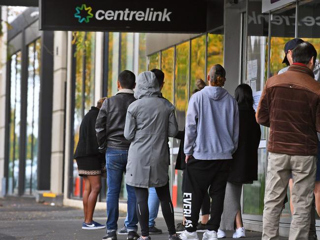 People queue up outside a Centrelink office in Melbourne on April 20, 2020, which delivers a range of government payments and services for retirees, the unemployed, families, carers and parents amongst others. - A report from the Grattan Institute predicts between 14 and 26 per cent of Australian workers could be out of work as a direct result of the coronavirus shutdown, and the crisis will have an enduring impact on jobs and the economy for years to come. (Photo by William WEST / AFP)