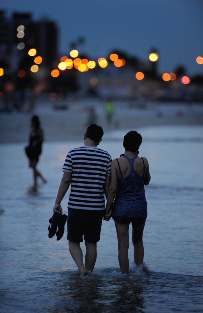 People enjoy a stroll through the cool water at Middle Park Beach. Picture: Andrew Henshaw