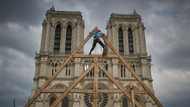 A member of the Charpentiers sans Frontiers (Carpenters without Borders) climbs a reconstruction of one of the missing timber frames of Notre-Dame Cathedral.