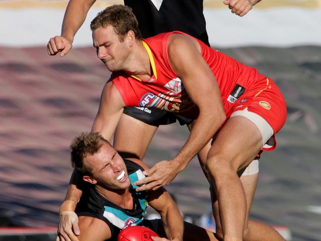 Port Adelaide’s Matt Thomas gets put into the ground by Jared Brennan.