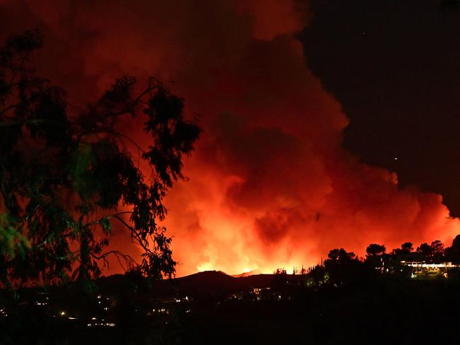 Smoke and flames from the Palisades Fire burn toward the Encino neighborhood of Los Angeles, California, January 10, 2025, triggering new evacuation orders. Massive wildfires that engulfed whole neighborhoods and displaced thousands in Los Angeles have killed at least 10 people, authorities said, as California's National Guard soldiers readied to hit the streets to help quell disorder. News of the growing toll, announced late Thursday January 9 by the Los Angeles County Medical Examiner, came as swaths of the United States' second-largest city lay in ruins. (Photo by AGUSTIN PAULLIER / AFP)