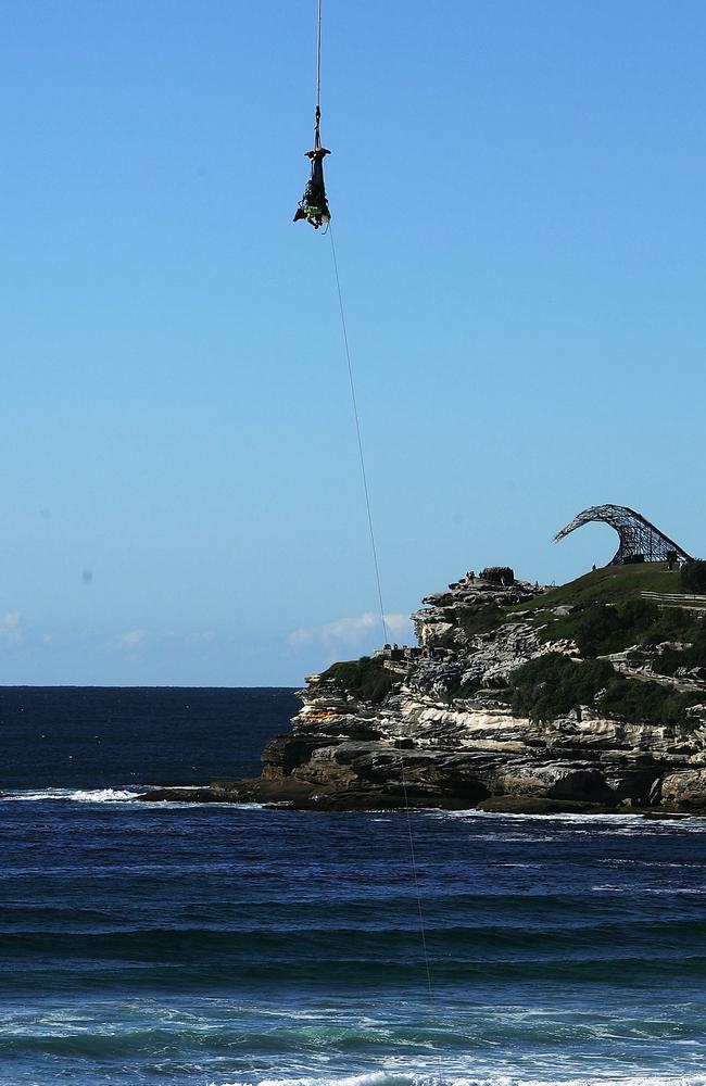 Hackett and Denyer are lowered to the sand after bungee jumping 300 metres out of a helicopter. Picture: Adam Pretty/Getty Images