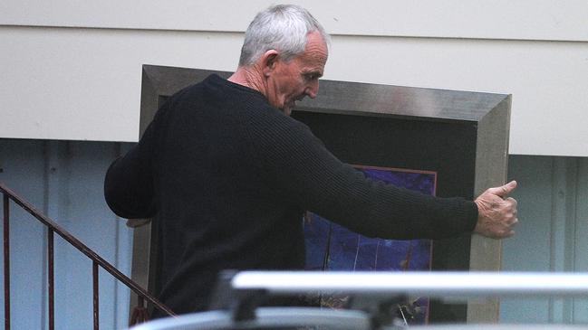 Logan councillor Russell Lutton removes a painting from a house in June.