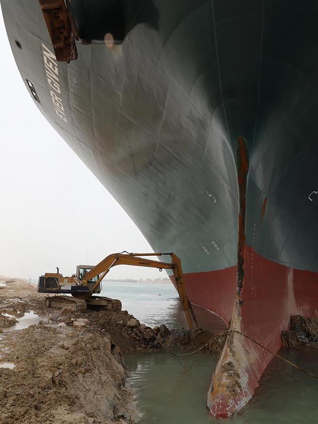 Massive task: A digger is dwarfed by the massive ship Picture: Suez Canal/AFP