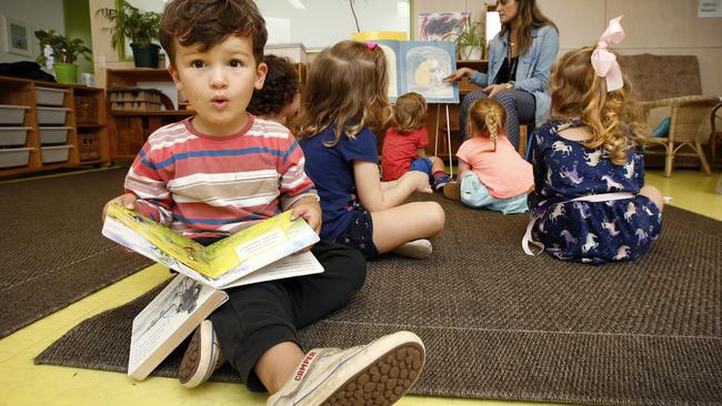 Asher 3, enjoys reading a book by himself as the teacher reads to the children at Civic Kindergarten Middle Park. Picture: David Caird