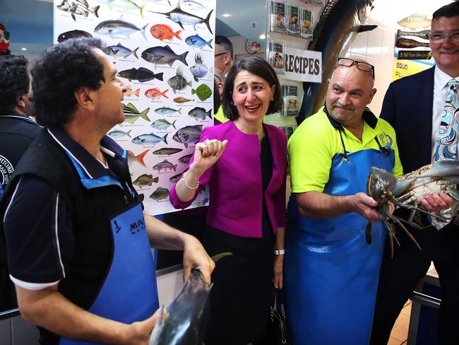 Gladys Berejiklian meets two of the workers at a seafood store during a visit to Seven Hills Plaza. Picture: Phil Hillyard