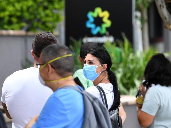People are seen wearing face masks in a long queue outside the Centrelink office in Southport on the Gold Coast, Monday, March 23, 2020. Centrelink offices around Australia have been inundated with people attempting to register for the Jobseeker allowance in the wake of business closures due to the COVID-19 pandemic.  (AAP Image/Dan Peled) NO ARCHIVING