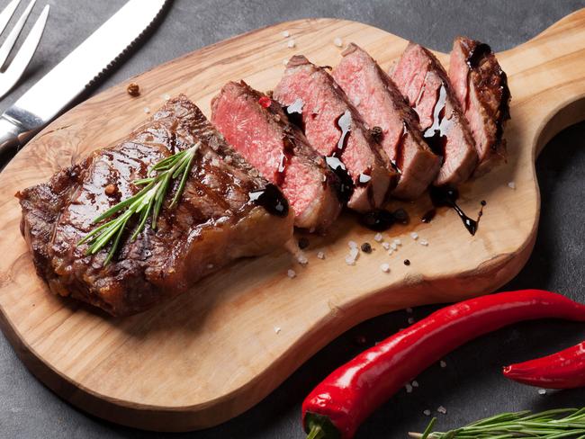 Grilled striploin sliced steak on cutting board over stone table