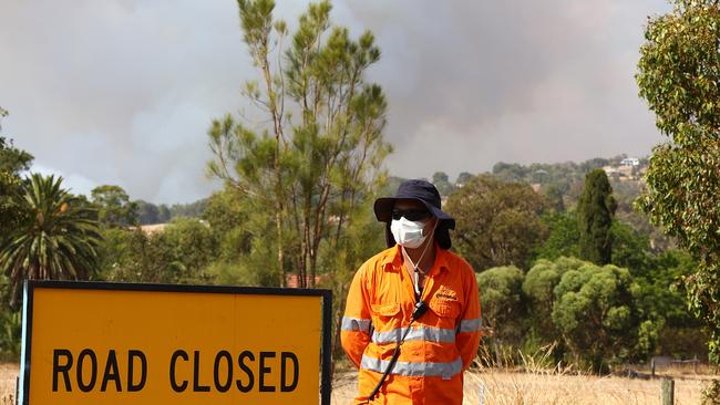 A traffic controller keeps watch at a road closure as a bushfire is seen threatening Avon Ridge in Brigadoon, Perth, on Wednesday. Picture: Getty Images