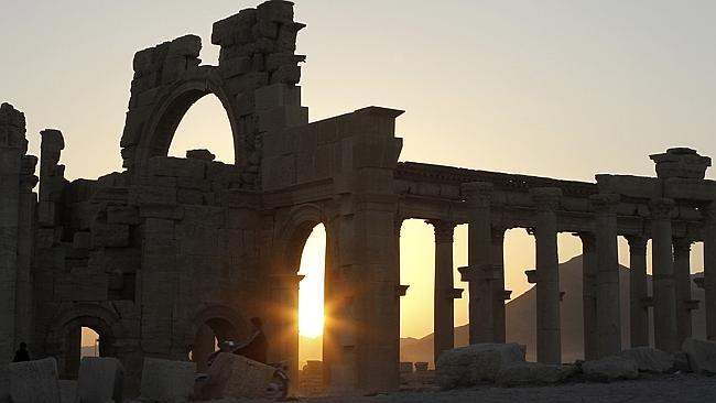 The sun sets behind ruined columns at the historical city of Palmyra, in the Syrian desert