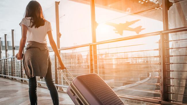 Covid safe travel etiquette tips.,  Photo: istock , Escape, 13 February 2022, Savvy,  Young woman pulling suitcase in  airport terminal. Copy space