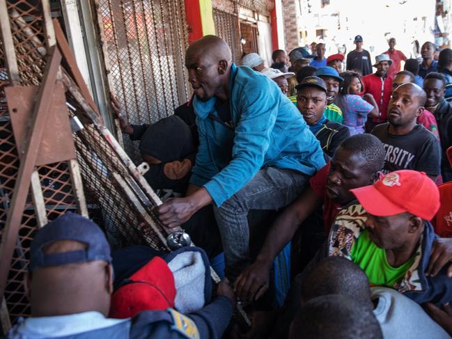 Looters try to break into an alleged foreign-owned shop during a riot in the Johannesburg suburb of Turffontein on September 2, 2019 as angry protesters loot alleged foreign-owned shops today in a new wave of violence targeting foreign nationals. (Photo by Michele Spatari / AFP)