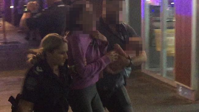 The victims are escorted away from the car by police in Hindley St. Picture: Nine News