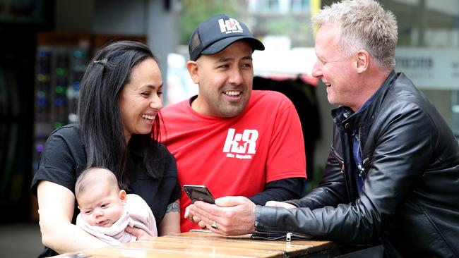 KidNest founder Tim Wise explains the app to Cesar Carreno and Adriana Castellanos, with seven-week-old daughter Camila. Picture: Mark Dadswell