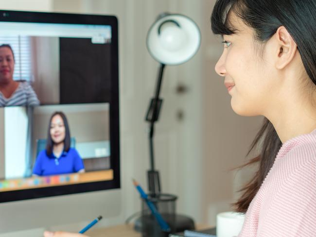 Back view of Asian business woman talking to her colleagues about plan in video conference. Multiethnic business team using computer for a online meeting in video call. Group of people smart working from home.