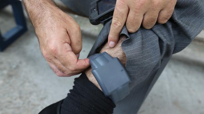 Picture of the device. Journalist Mark Morri wearing an electronic monitoring bracelet. Fitted at Silverwater Correctional Complex and then walking around Silverwater entering a predifined restricted zone.