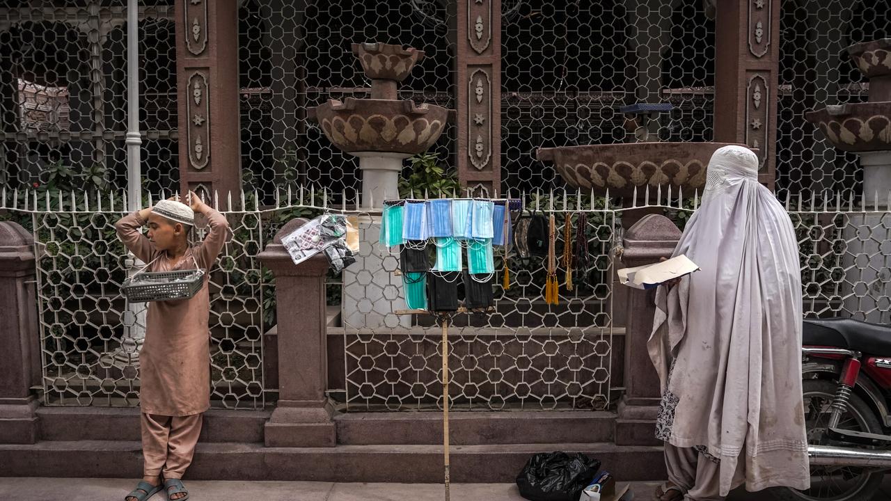 A street vendor in a burqa and a child sell face masks in Peshawar, Pakistan. Picture: Danial Shah/Getty Images