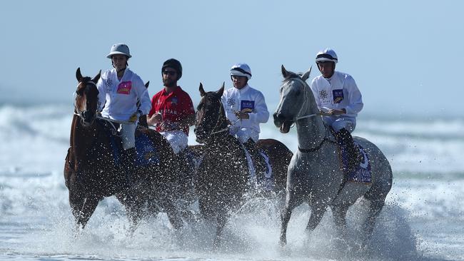 Jockeys ride through the water during the 2022 Magic Millions Barrier Draw at Surfers Paradise. Picture: Chris Hyde/Getty Images