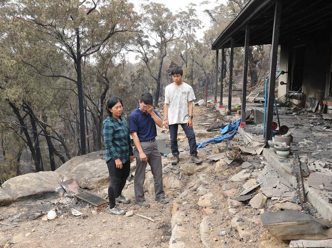 Gabriel Cam with his parents Helena and Justin at the burnt ruin of their Balmoral home. Picture Rohan Kelly