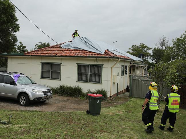 Emergency Service crews putting tarps on a house that was damaged in s hail storm. Picture: Tim Hunter.