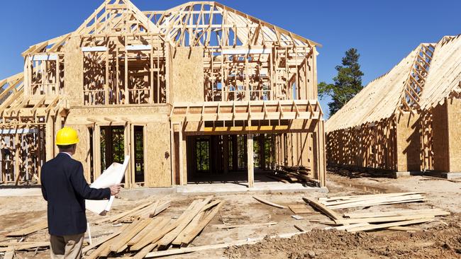 Developing Queensland - New home construction site with contractor in foreground.