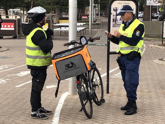 A police officer speaks with a food delivery rider on Wednesday near The Corso. Picture: Jim O'Rourke